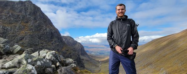 Nick standing at the peak overlooking a sunny valley